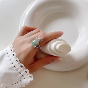 Detail of vintage silver branch ring with oval light green gemstone worn by a model