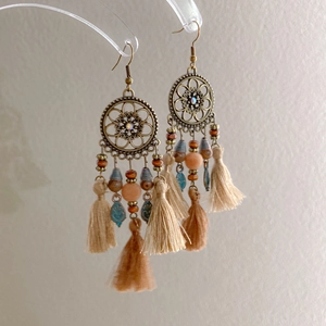 Close-up of bohemian drop earrings with bronze metal, colorful beads and soft tassels