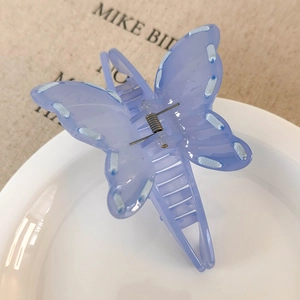 Detail shot of a purple ribbon bow hair claw clip placed on a white ceramic plate