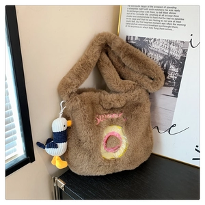 Detail of brown plush tote bag with sweet donut embroidery and a seagull plush charm