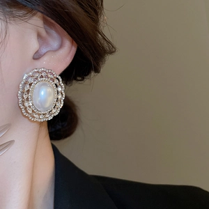 Close-up of gold-plated French style stud earrings with white pearl and pave zircon stones