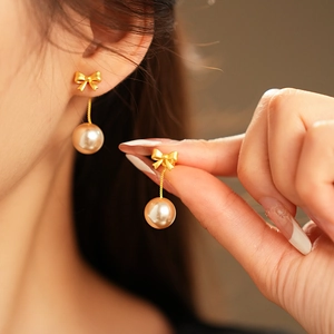 Detail of golden bow pearl drop earrings showing champagne pearl and elegant design