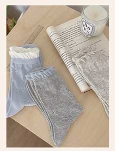 Detail of light blue and grey knit socks with ribbon jacquard and ruffle cuff on wood