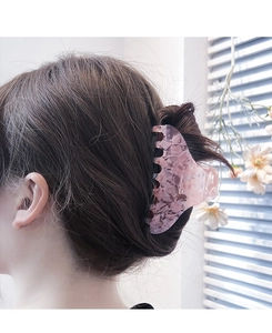 Detailed view of a large pink marble acetate hair claw clip worn by a model in soft light