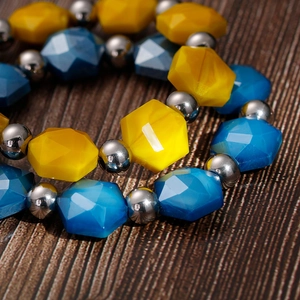 Close-up of bohemian beaded bracelet featuring yellow and blue faceted crystal hexagon beads