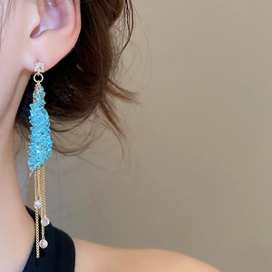 Model wearing elegant blue beaded and gold chain tassel earrings with square crystal studs