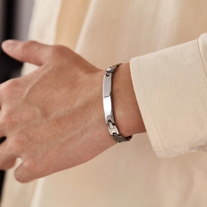 Close-up of a silver stainless steel curb chain bracelet with rectangular plate on male wrist