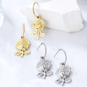 Macro detail of rose-shaped earrings in gold and silver finish with petal textures