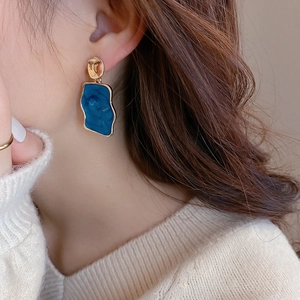 Primo piano di orecchini geometrici irregolari oro e blu stile pittura a olio su modella