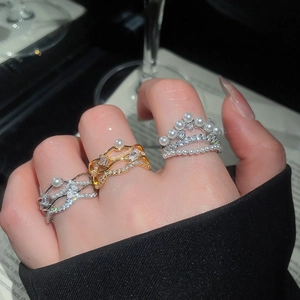 Detailed view of layered 18k gold plated rings featuring zircon stones and pearls on hand