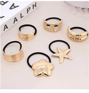 Detail showing various irregular golden alloy charms on black elastic hair ties