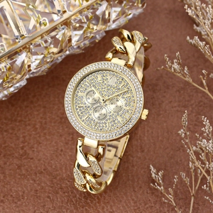 Close-up of gold iced-out watch with crystals on a textured background with decor