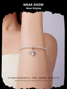 Detail of silver mesh bracelet with purple pear-shaped gemstone and heart pendant on wrist