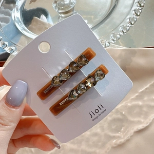 Detail of amber heart hair clips with grey rhinestones on an elegant jewelry display card
