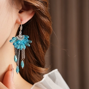 Détail de boucles d'oreilles bohèmes en forme d'éventail avec pompons en cristal bleu