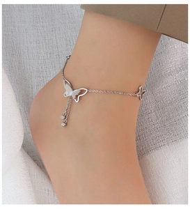 Detailed close-up of a silver butterfly anklet featuring tassels and a star charm