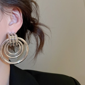 Nahaufnahme eines Models mit geschichteten silbernen Creolen im modernen Mehrkreis-Design