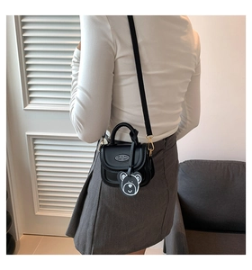 Mini black crossbody bag detail showing the bear charm and sleek leather finish