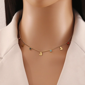 Golden heart necklace with colorful round gemstone pendants worn by a fashion model