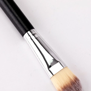Flat foundation brush with black matte handle and dual-tone synthetic bristles on white background