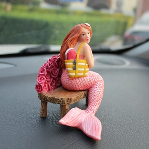 Charming mermaid figurine with pink tail on a rose-covered bench for car dashboard decor
