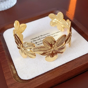 Détail d'un bracelet ouvert doré aux motifs floraux ciselés sur un présentoir de luxe