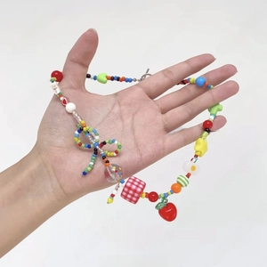 Detailed close-up of colorful Y2K beaded necklace with red heart and apple charms