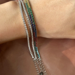 Close-up of three S925 sterling silver tennis bracelets with sparkling stones on wrist