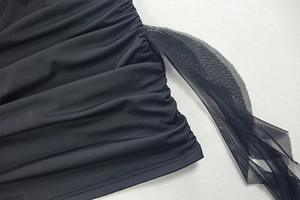 Détail de la robe courte moulante noire montrant la texture froncée et le tulle