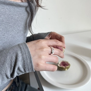 Detailed view of a silver geometric diamond-cut ring on a model's finger