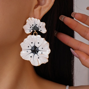 On-ear detail of ginkgo flower enamel earrings in black and white with gold edges