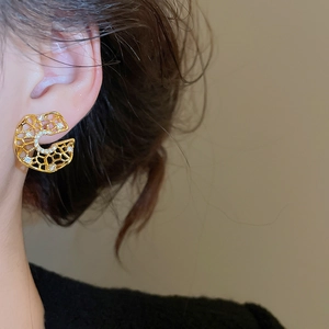 Macro side view of gold hollow honeycomb earrings with zircon on a model's ear