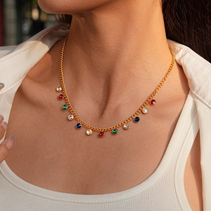 Detail of model wearing gold chain necklace with colorful round gemstone pendants