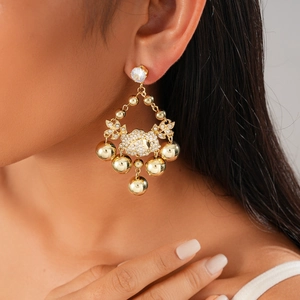Detailed close-up of golden tassel earrings with white zircons on a model