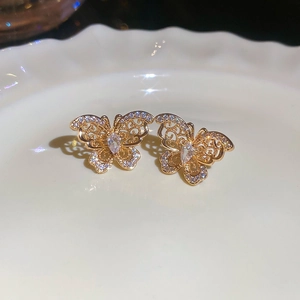 Detail shot of gold butterfly earrings with cubic zirconia on a white ceramic plate