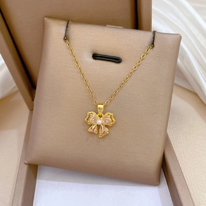 Close-up of pink bow pendant necklace with crystals and pearl on a golden chain