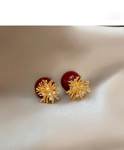 Detail of red floral earrings with gold accents and zircons on champagne silk