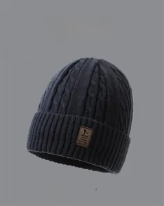 Detail of dark gray cable knit beanie with premium brown leather brand label