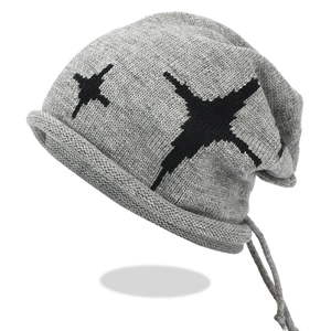 Detail of grey knitted beanie featuring star patterns and drawstring design texture