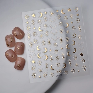 Star and moon gold foil nail art stickers set with celestial patterns on light pink nails