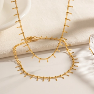 Detail of 18K gold plated stainless steel necklace and bracelet set with small pendants