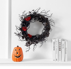 Detail of Halloween wreath with black twigs and red roses hanging on a white fireplace