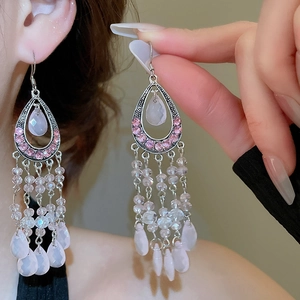 Macro detail of bohemian silver earrings with pink teardrop glass stones and tassels