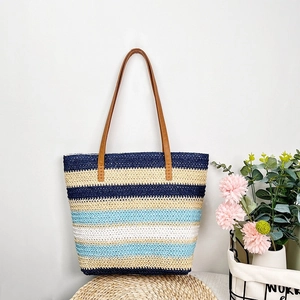 Detailed macro view of woven straw beach tote bag with colorful striped embroidery texture