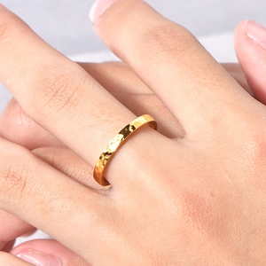Minimalist 18K gold plated titanium ring with irregular hammered texture on model's finger