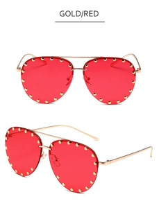 Detail view of gold aviator sunglasses with red lenses and metallic rivet studs decor