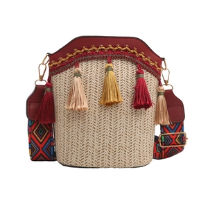 Detail of woven straw bag with tassels, red PU leather trim and geometric pattern strap