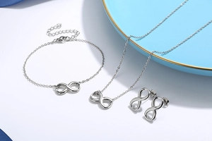 Silver jewelry set with infinity symbol necklace, bracelet and earrings on blue plate