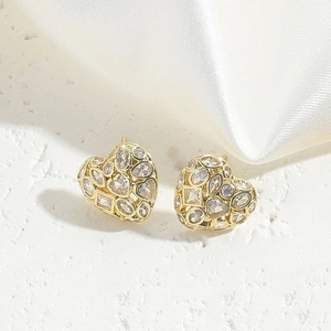 Macro detail of heart-shaped gold earrings with multi-cut sparkling cubic zirconia stones