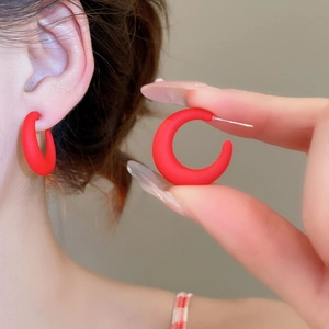 Close-up of matte wine red C-shaped acrylic earrings with a smooth frosted finish